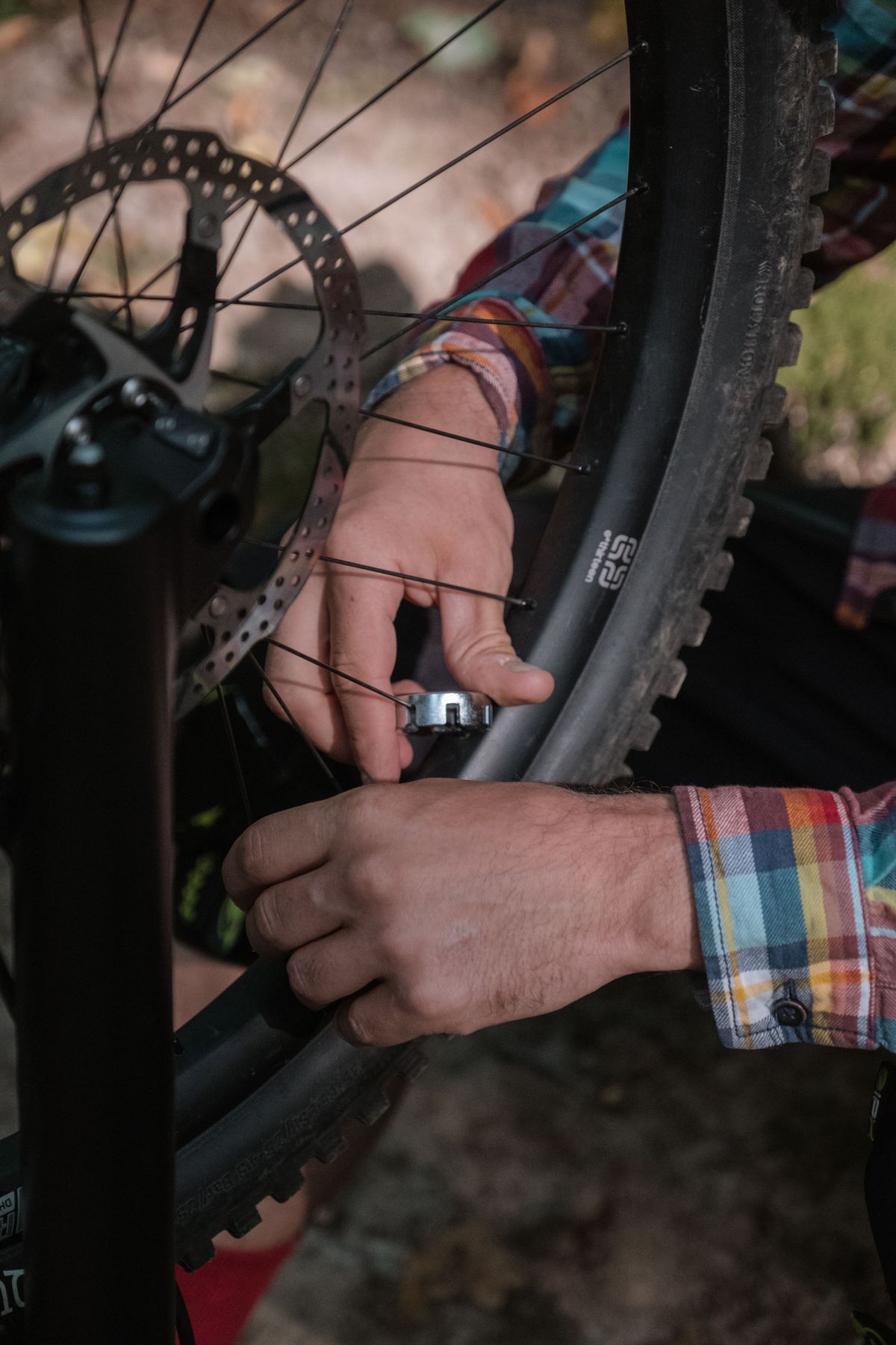 Close-up of hands adjusting a bicycle wheel with tools outdoors