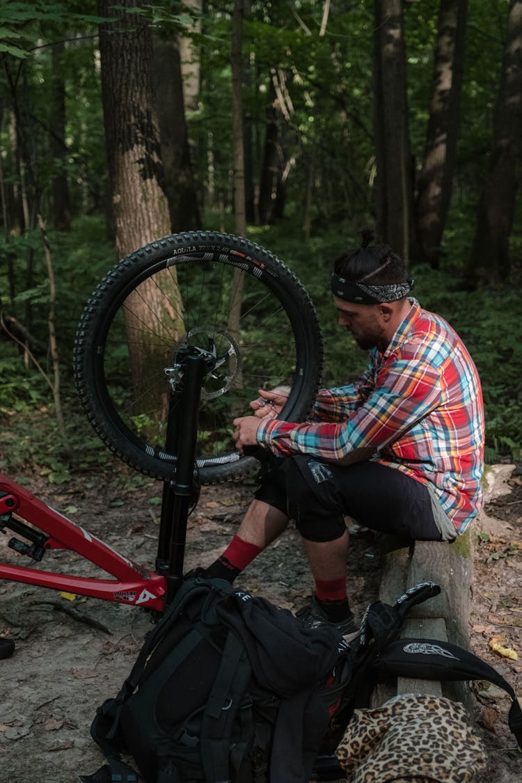 Photo Of A Man In A Plaid Shirt Fixing His Bicycle Wheel