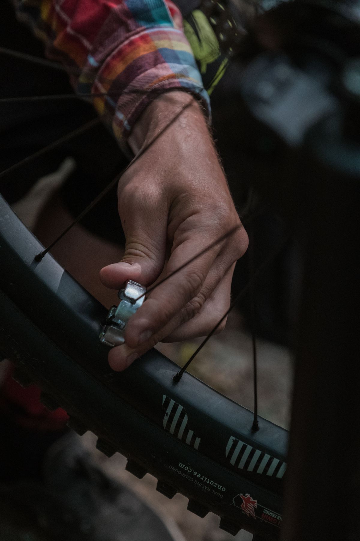 Hands using a tool to adjust the spokes of a bicycle wheel