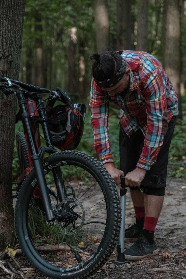 Photo Of Man In A Plaid Shirt Pumping His Bicycle Tire