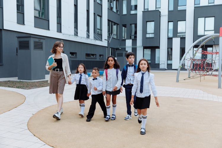 Teacher And Students Walking Around The School Campus