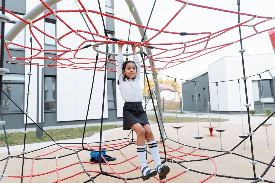Mädchen klettert auf einem Spielplatz