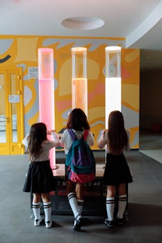 Three girls explore a science experiment with colorful liquids at school, promoting educational curiosity.