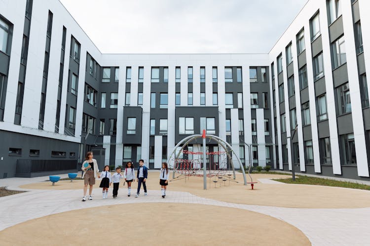 Teacher And Students Walking Around The School Campus