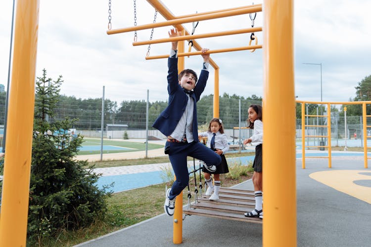 An Active Boy Hanging On Monkey Bars