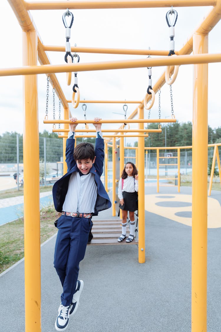 An Active Boy Hanging On Monkey Bars