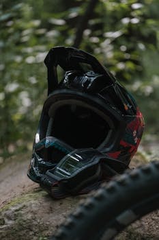 Close-up of a mountain biking helmet resting on a forest trail, emphasizing safety and adventure.