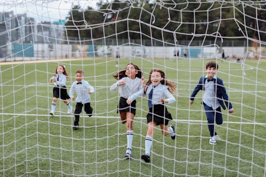 Group of children joyfully running towards the camera on a soccer field, showcasing a lively and playful moment.