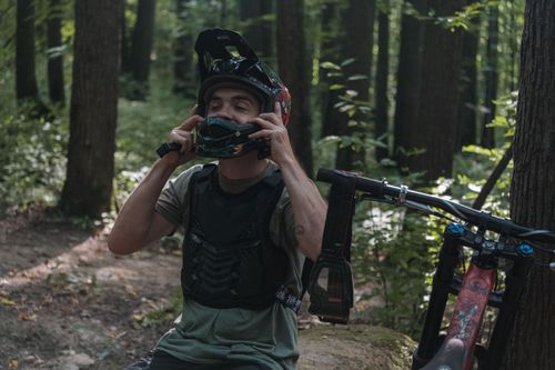 Free Man adjusting helmet for mountain biking in a lush forest setting. Stock Photo