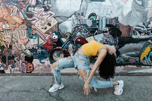 Woman in a Yellow Top Dancing Beside a Wall with Graffiti