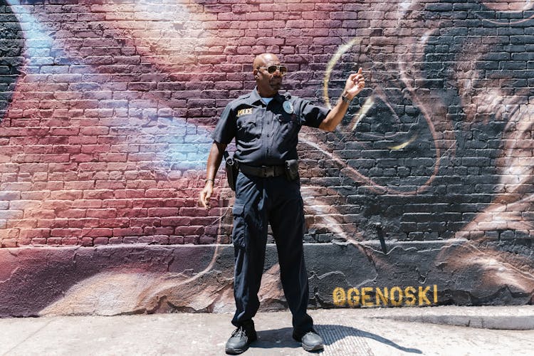 A Policeman Standing In Front Of A Brick Wall