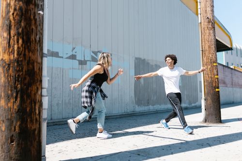 Free Two young adults dancing energetically on an urban street under clear blue skies. Stock Photo