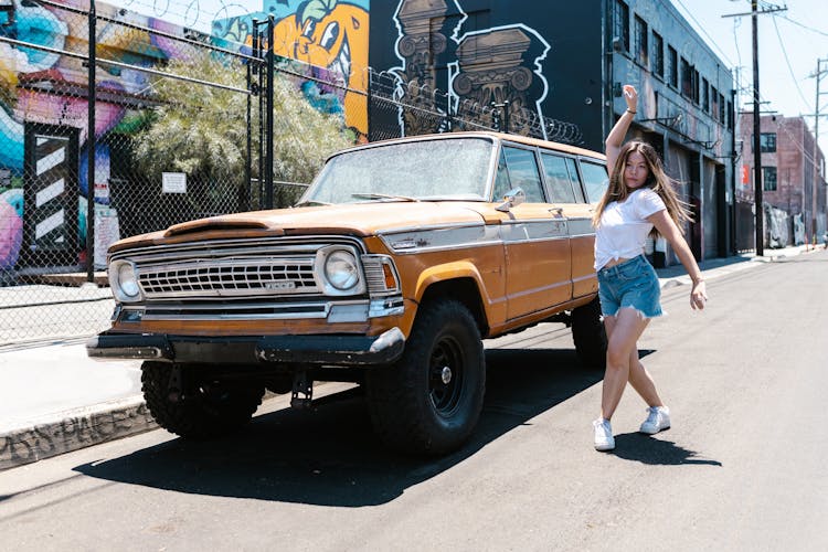 Woman In White T-shirt Dancing Beside The Orange Car