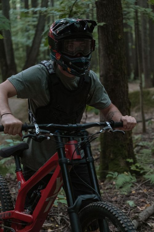 Free A mountain biker wearing a helmet rides through dense forest, showcasing outdoor adventure. Stock Photo