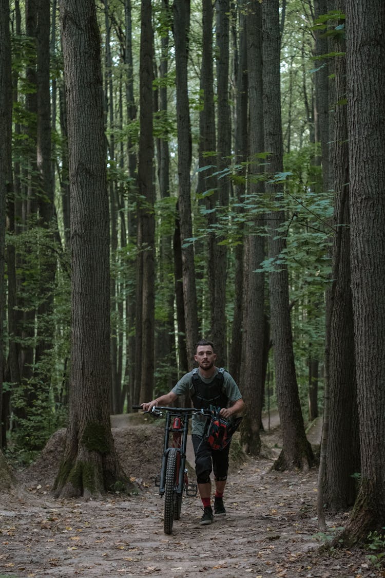 Woman Walking In The Woods While Holding A Bicycle