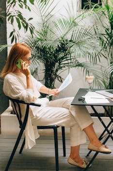 Professional woman working on documents and phone in a serene outdoor office setting.