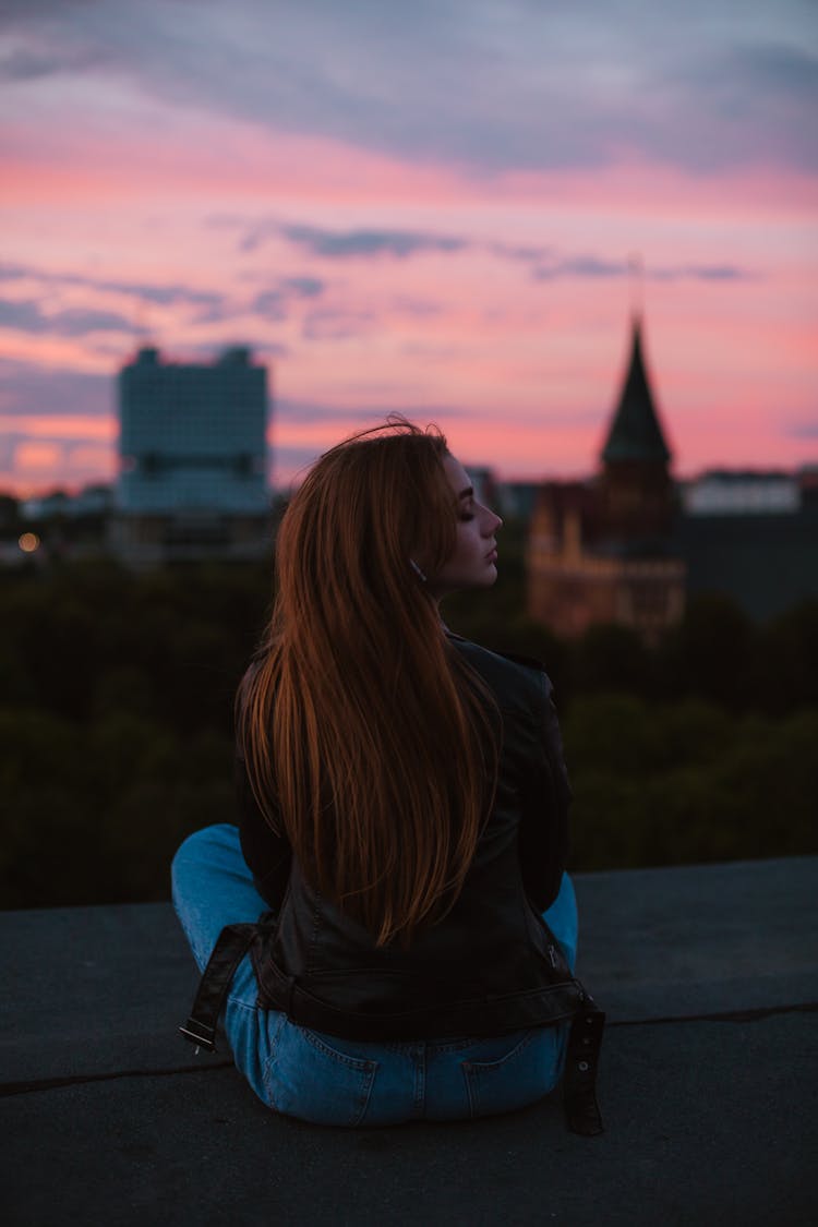 Back View Of A Young Woman Sitting On The Ground