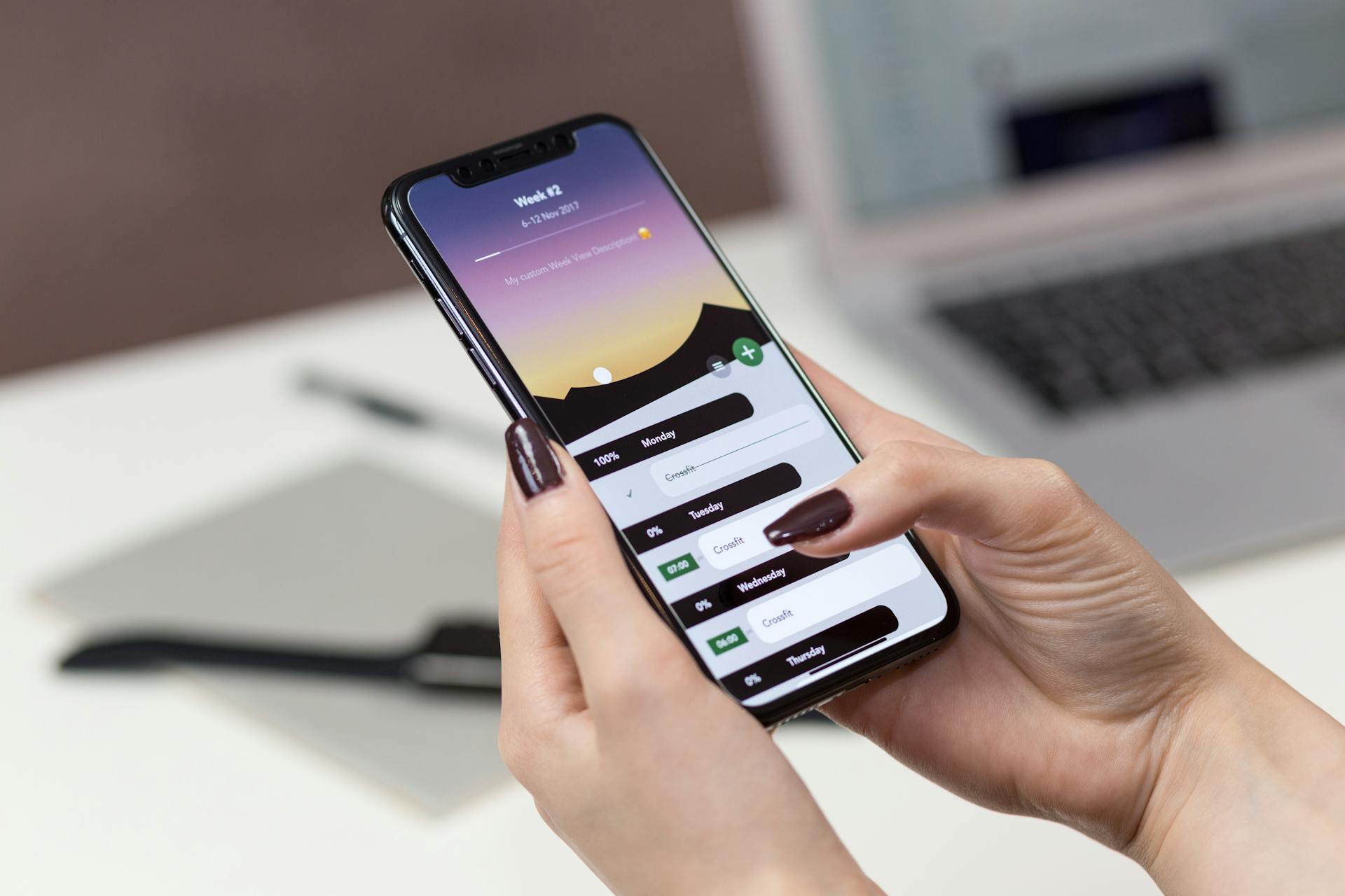 A woman interacts with a productivity app on her smartphone at a desk setup.