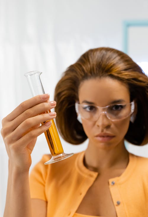 Woman in Yellow Top Holding a Graduated Cylinder