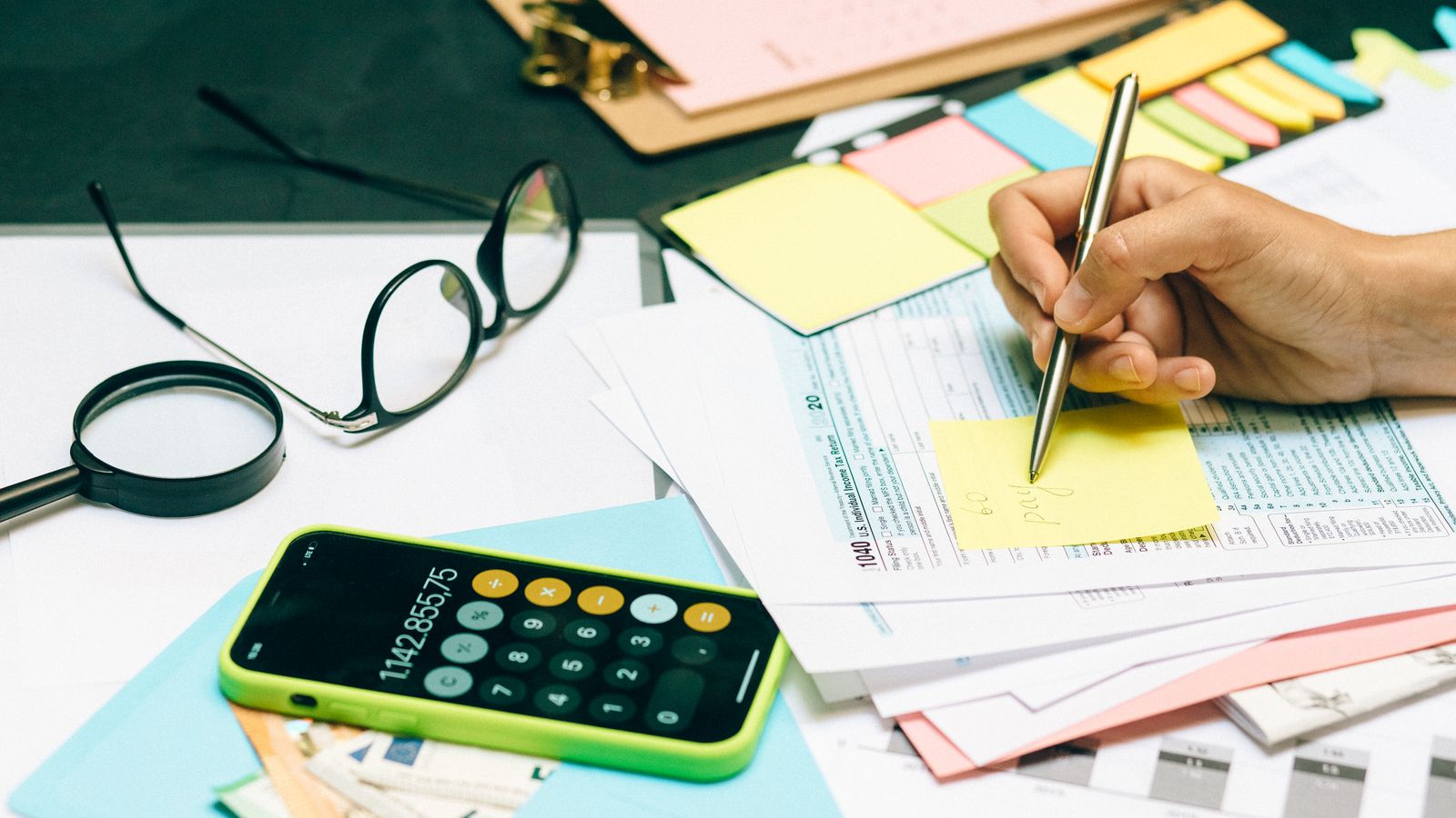 Close-up of an office desk with a calculator, glasses, and documents for financial planning.