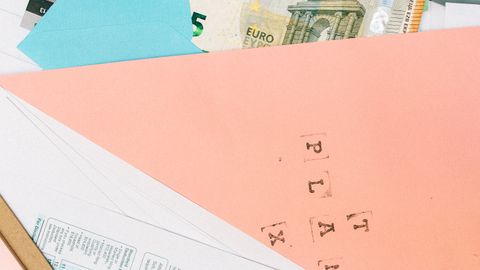 Close-up of colorful envelopes containing Euro notes and various papers, symbolizing financial planning.