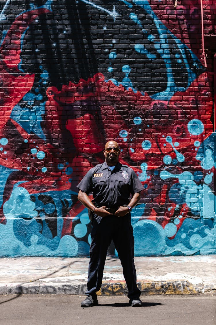 Man In Police Uniform Against Mural