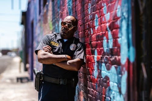 Free A Policeman Leaning on a Brick Wall Stock Photo