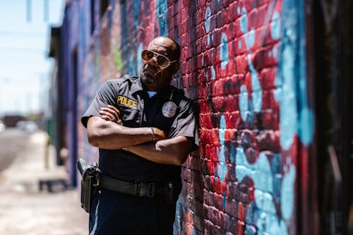 A Policeman Leaning on a Brick Wall