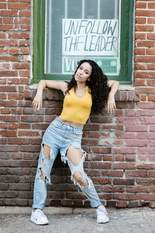 Woman in a Yellow Top Posing Near a Brick Wall