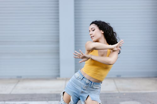Free Woman in Yellow Crop Top and Ripped Denim Jeans Dancing Stock Photo