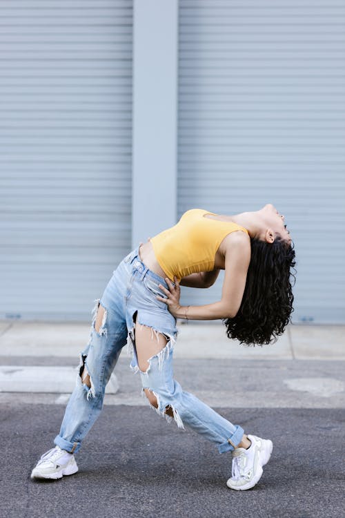 A Woman in Tattered Jeans Bending Her Body