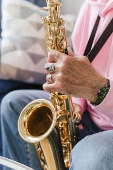 A person wearing rings plays a golden saxophone with a focus on their hands.