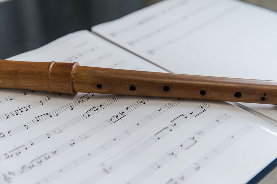 Close-up of a wooden soprano recorder resting on an open sheet music book