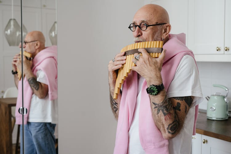 An Elderly Man Playing The Pan Flute Indoors