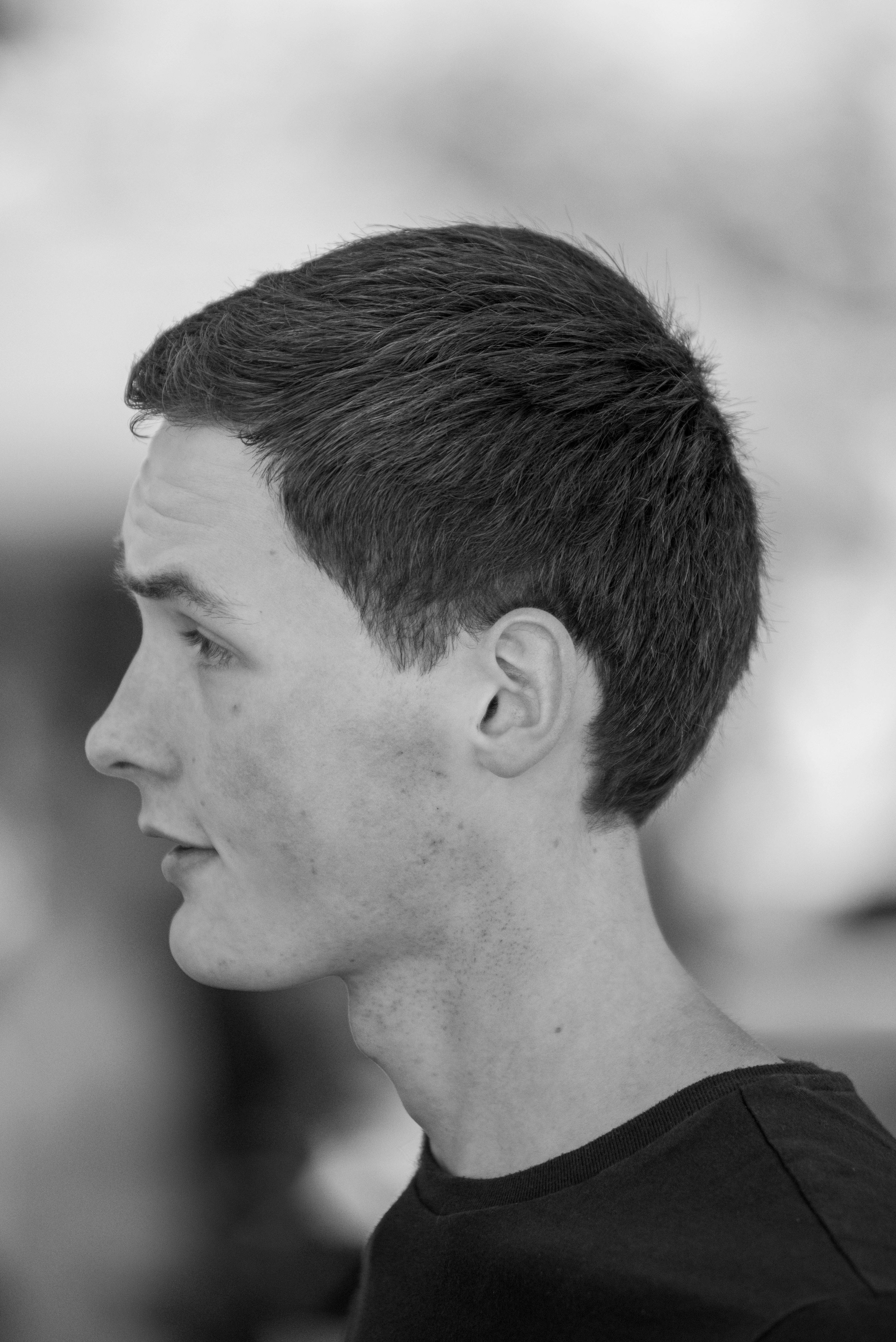 A grayscale side profile of a young man showcasing his hairstyle and thoughtful expression.