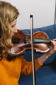 A woman playing a violin indoors, showcasing musical focus and artistic expression.