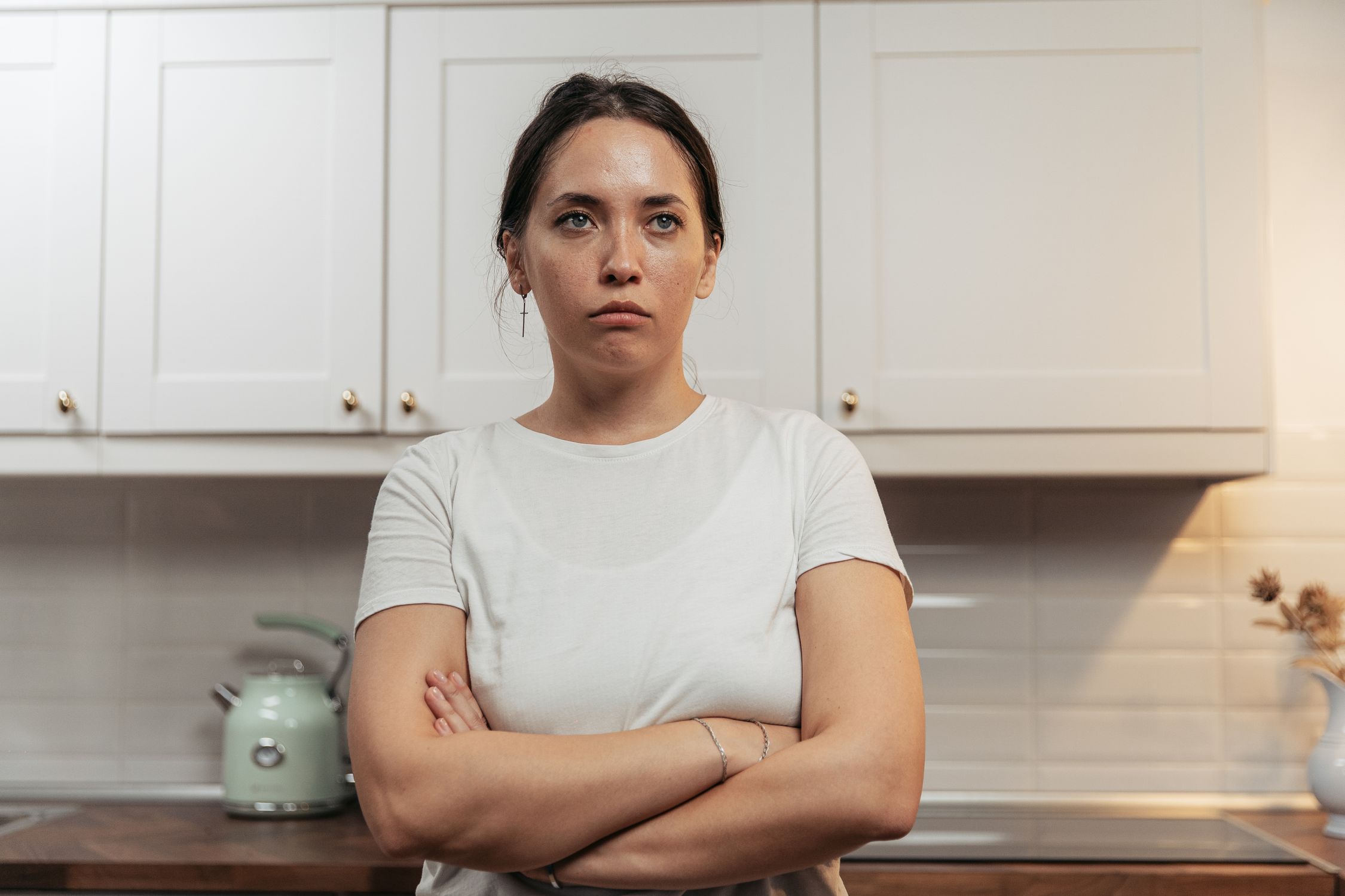 Mulher em momento de angústia na cozinha, refletindo o uso do controle alimentar como alívio para ansiedade