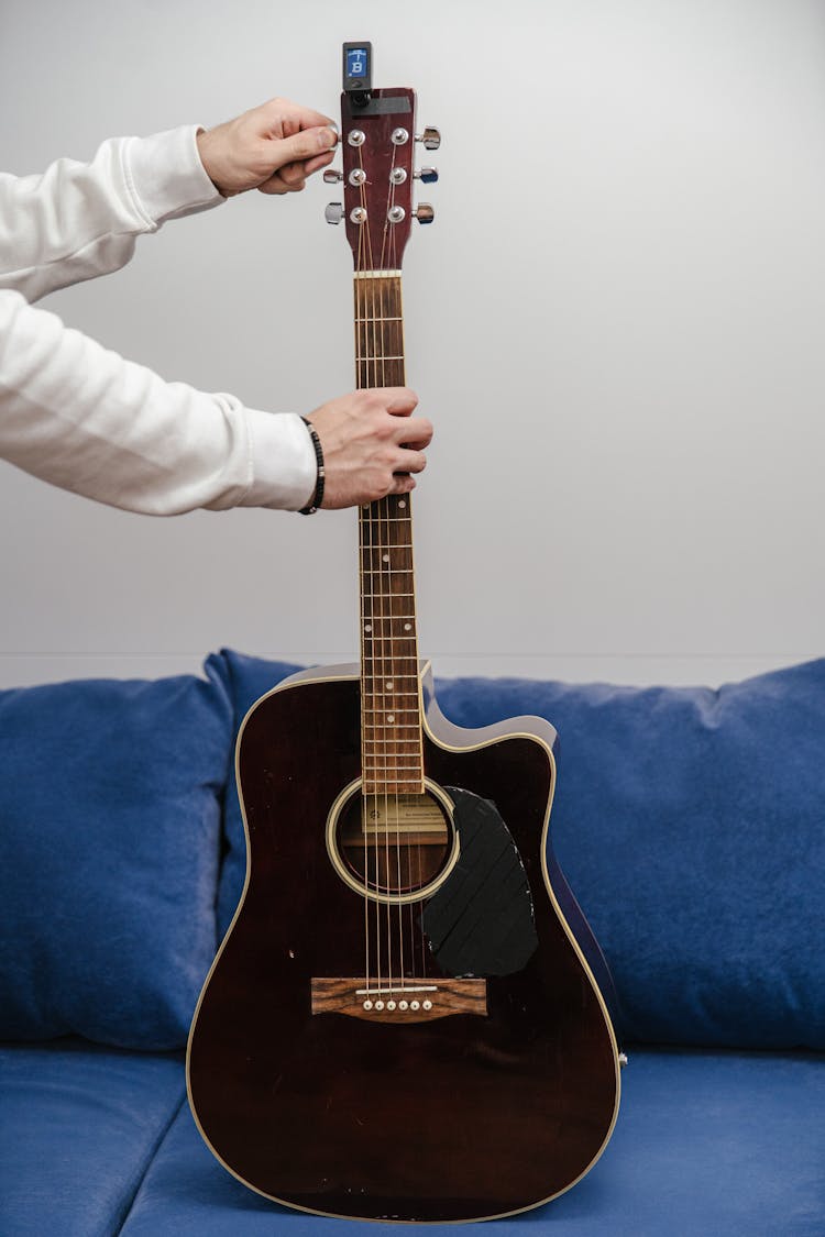 A Person Tuning An Acoustic Guitar