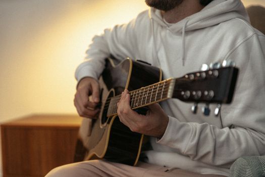 A person playing acoustic guitar indoors, capturing a cozy and relaxed atmosphere.