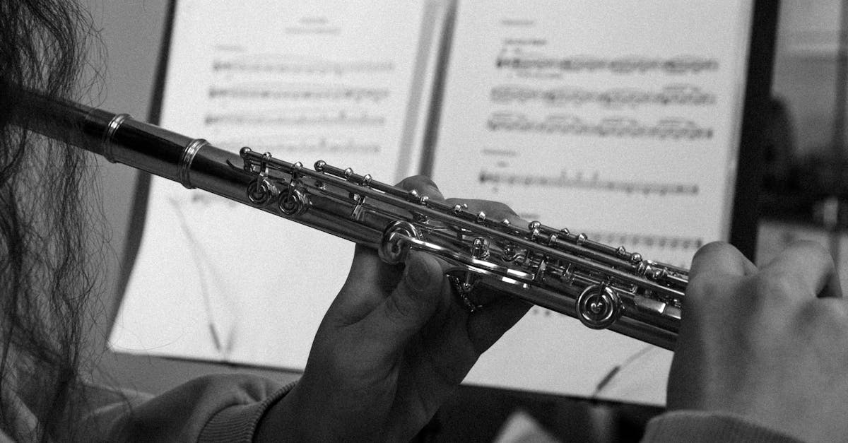 Black and white image of a flutist playing with sheet music in the background.