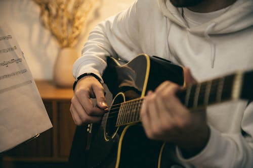 Бесплатное стоковое фото с акустическая гитара, белый свитер, бренчание