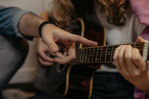 Person Playing Brown Acoustic Guitar