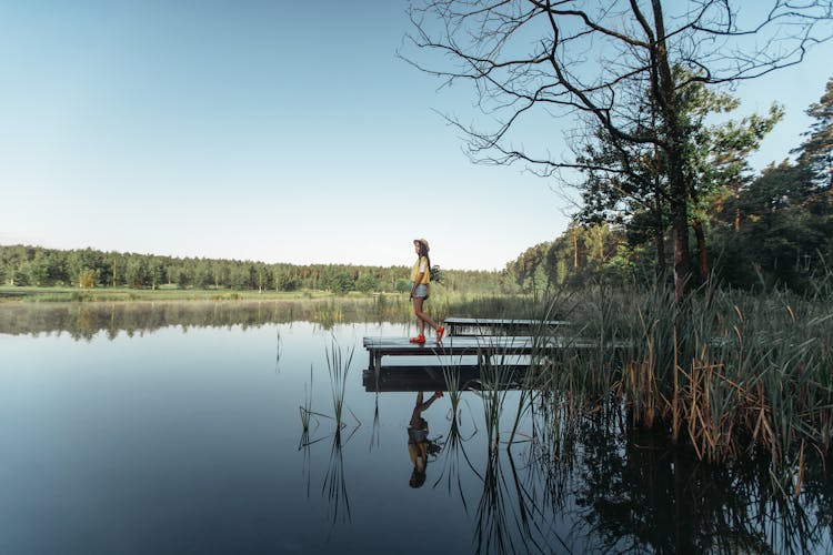  A Woman Walking On A Dock By The Lake