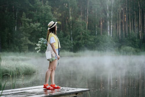 A Woman Standing Near a Foggy Lake