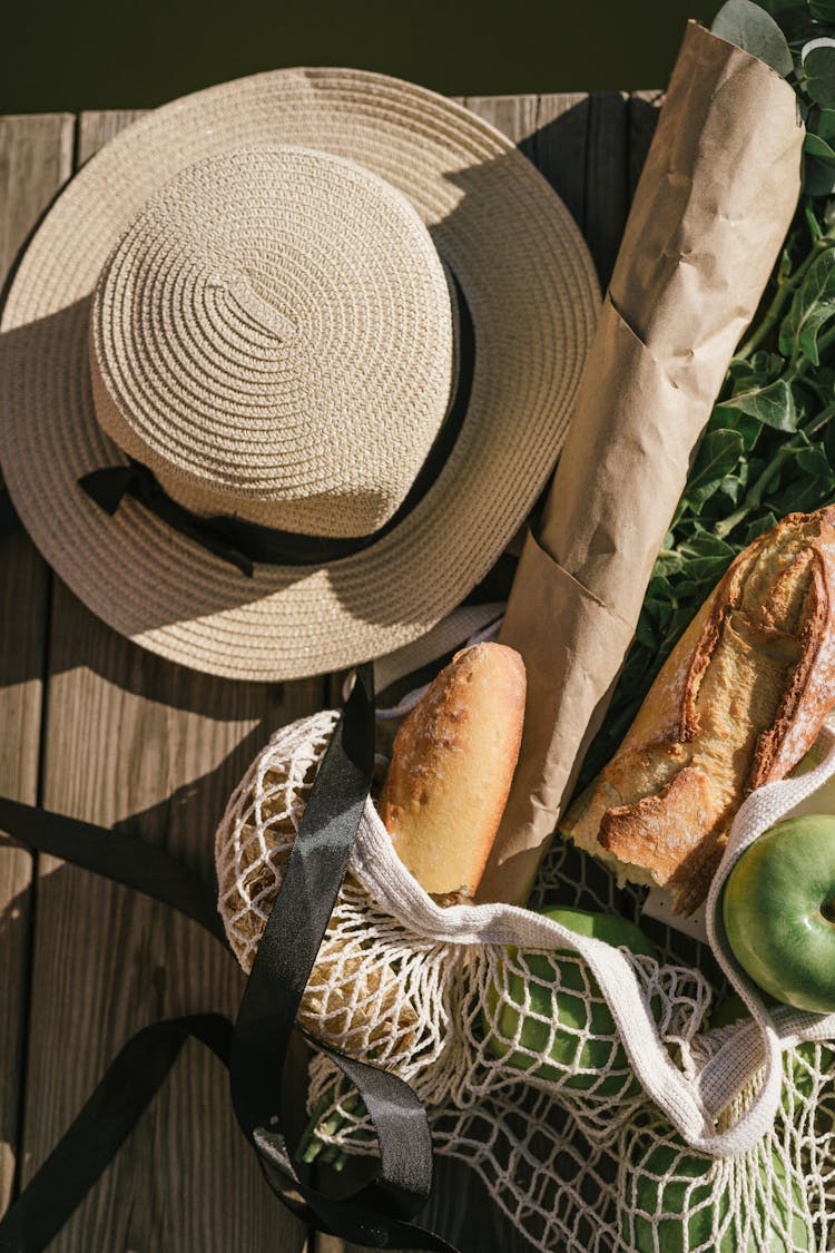 Summer Hat And Food In A Bag Lying On A Wooden Pier 