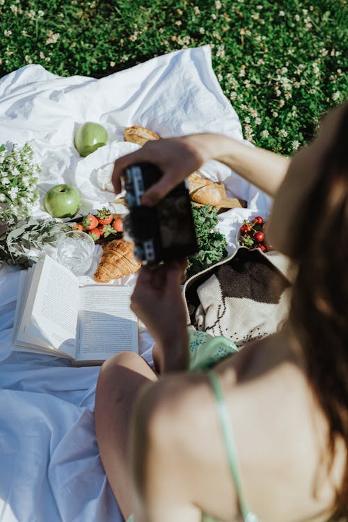 Back View Shot of a Woman Taking Photos of the Foods on the Picnic Blanket 