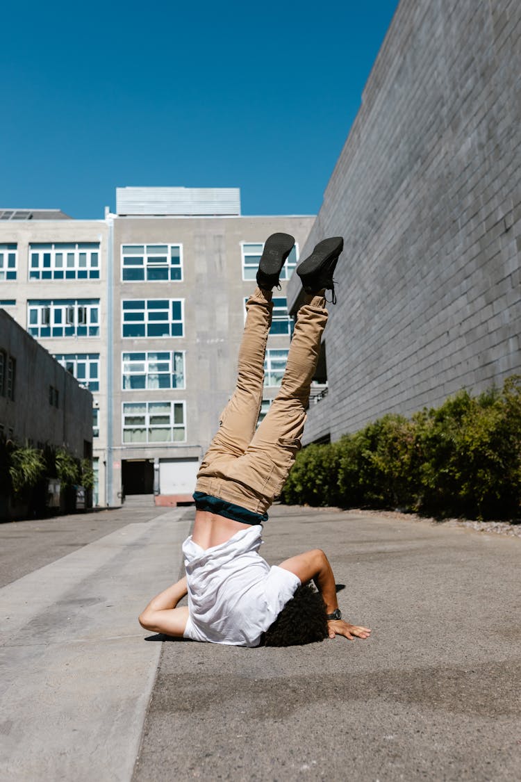 A Person In White Shirt Doing Head Stand