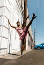 A Woman in Pink Dress Standing on the Street while Raising Her Legs