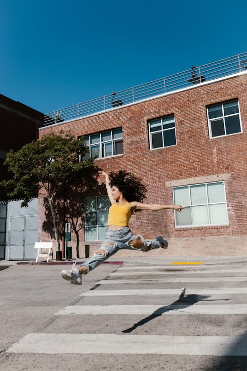 A Woman in Yellow Tank Top Jumping on the Street