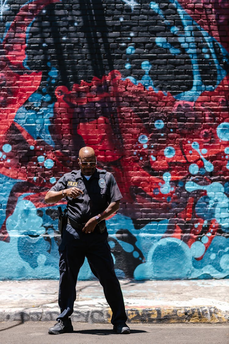 A Policeman Standing Near The Graffiti Wall 